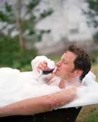 Man sipping on wine in a bathtub