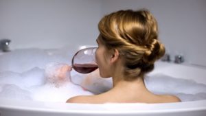 Woman sipping on wine in a bathtub
